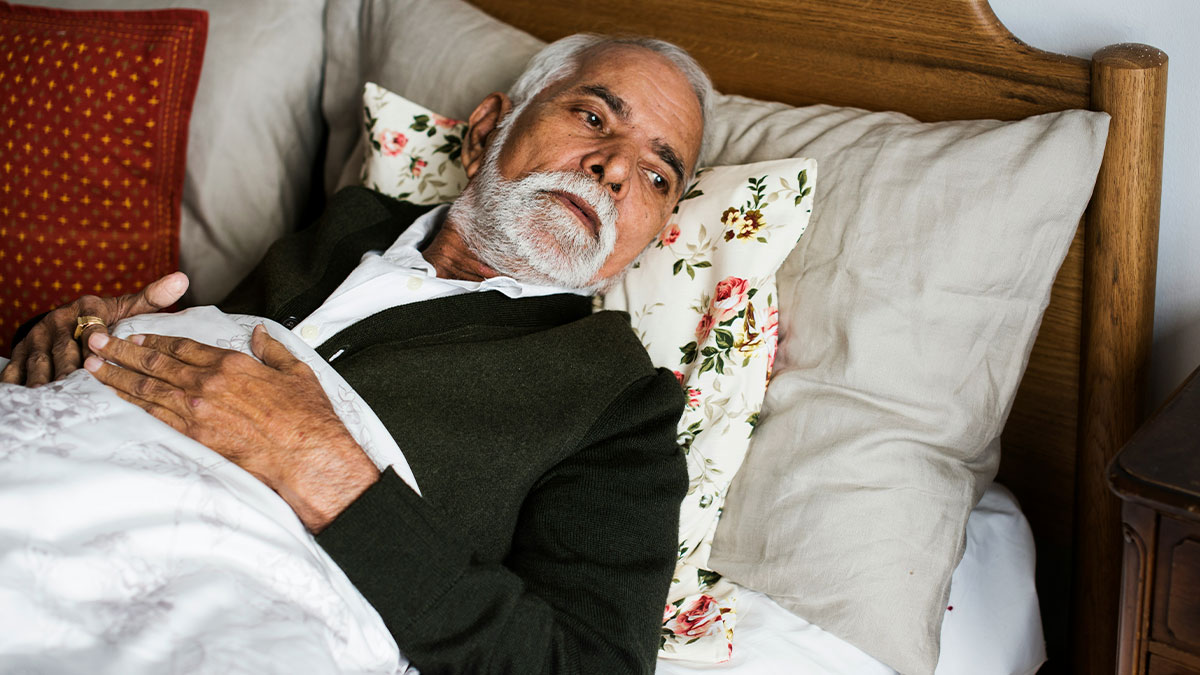 Elderly man in bed looking contemplative, symbolizing choosing funeral over first look at daughter and pregnant wife.