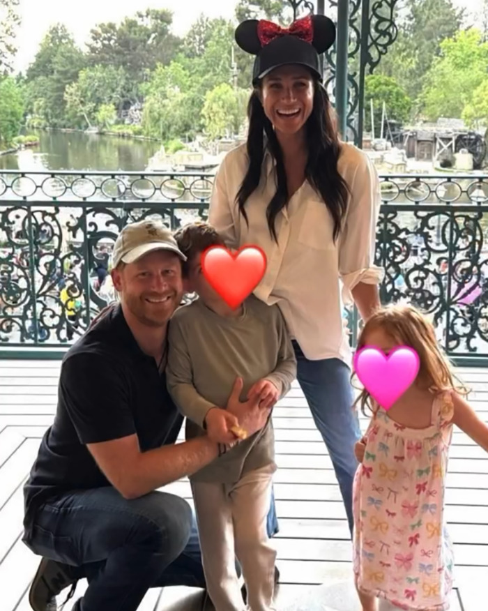 Meghan Markle with family outdoors, children’s faces covered with heart emojis, casual setting near decorative railing. Meghan Markle with family outdoors, children’s faces covered with heart emojis, casual setting near decorative railing.