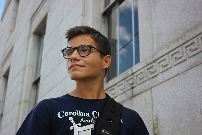 Young man wearing glasses and a dark shirt standing outside a stone building, symbolizing absent grandma reconnecting after 25 years. Young man wearing glasses and a dark shirt standing outside a stone building, symbolizing absent grandma reconnecting after 25 years.