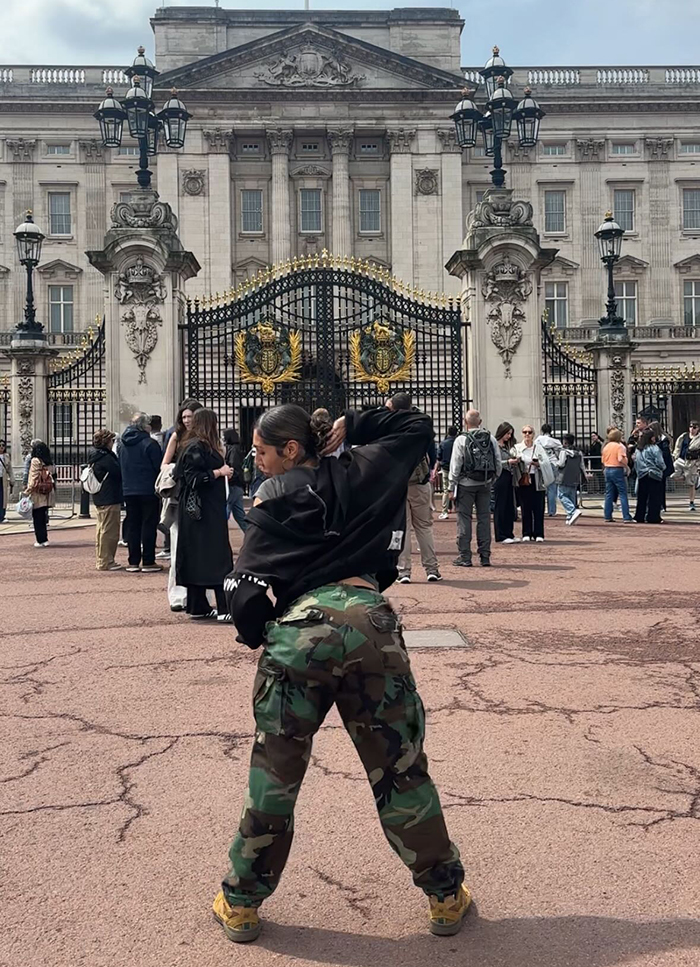 Person in camouflage pants posing in front of Buckingham Palace gates, related to Aboriginal artist and King Charles debate. Person in camouflage pants posing in front of Buckingham Palace gates, related to Aboriginal artist and King Charles debate.