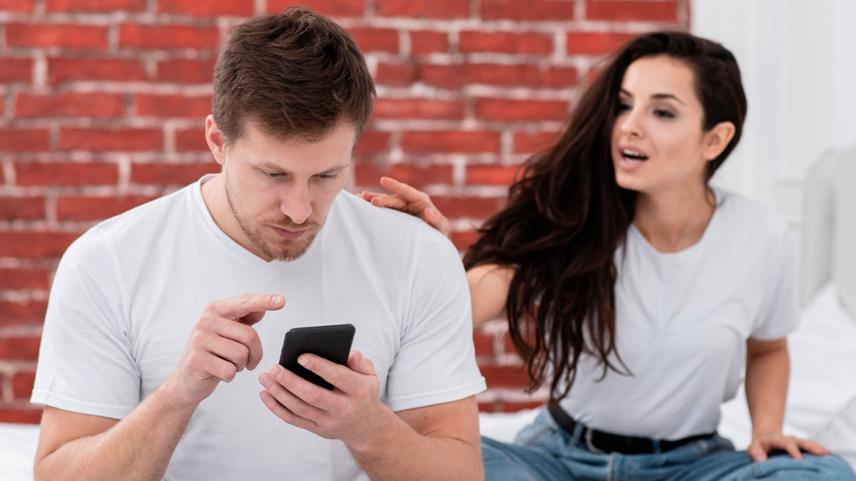 Young couple in casual clothes showing modern dating struggles with man focused on phone and woman reaching out to him.