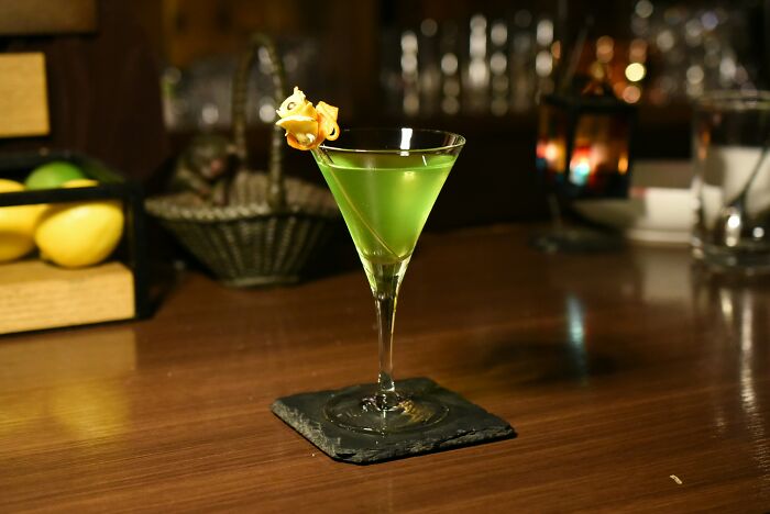 Green cocktail in a martini glass on a bar counter, representing dates that went sour in a bar setting.