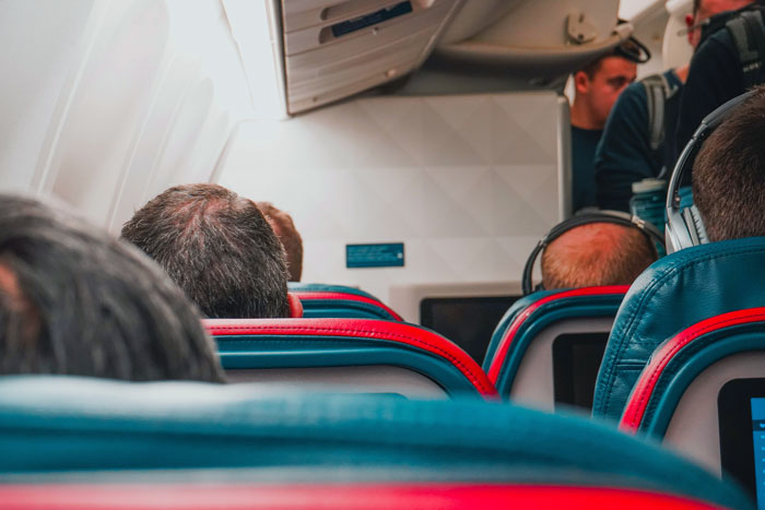 Airplane interior with passengers seated and an obnoxious guy about to slap a napping passenger’s head for attention. Airplane interior with passengers seated and an obnoxious guy about to slap a napping passenger’s head for attention.