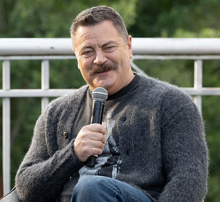 Nick Offerman holding a microphone, wearing a gray cardigan, praised for a brutal clapback against homophobe. Nick Offerman holding a microphone, wearing a gray cardigan, praised for a brutal clapback against homophobe.