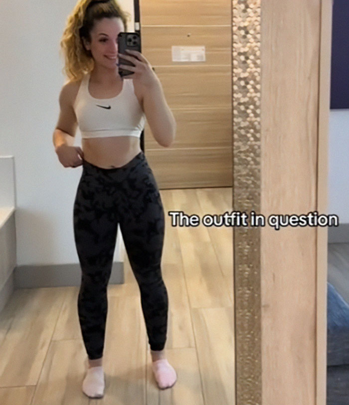Woman taking mirror selfie wearing athletic top and leggings, relating to Disney staff complaint about inappropriate outfit. Woman taking mirror selfie wearing athletic top and leggings, relating to Disney staff complaint about inappropriate outfit.