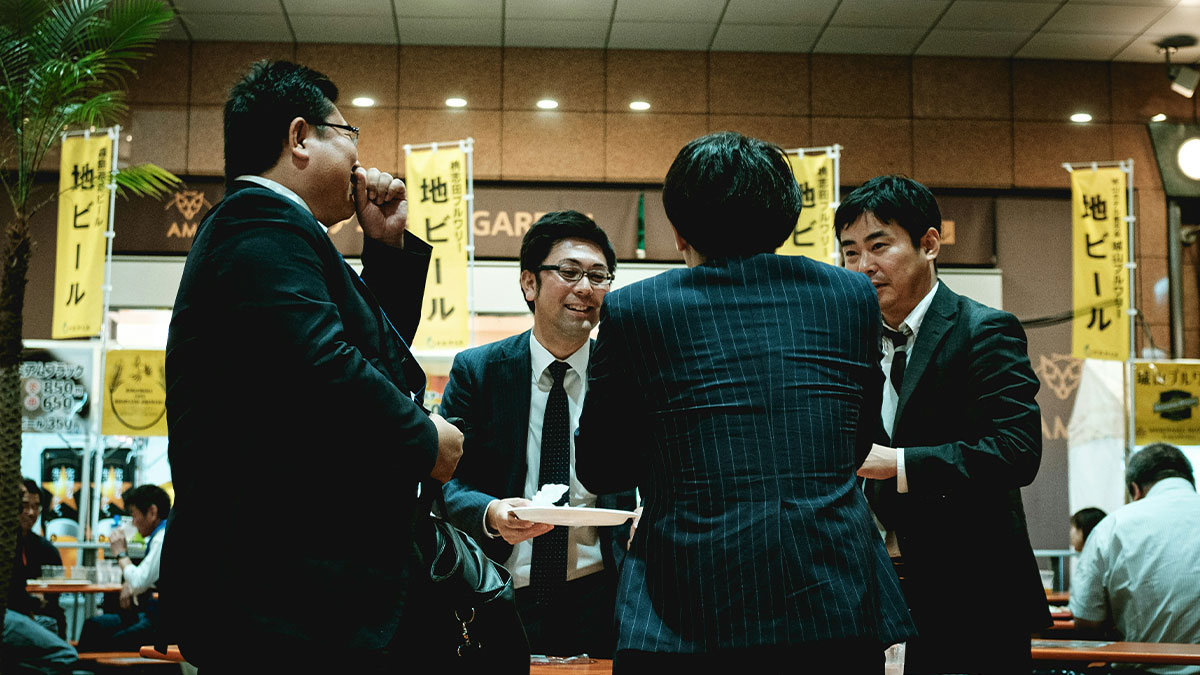 Group of businessmen socializing in a Japanese bar highlighting the shortcomings of being big in Japan in real life.