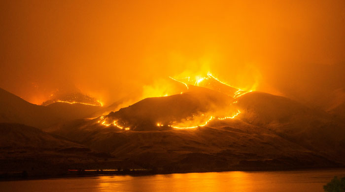 Wildfire blazing across hills at night, symbolizing cosmic chaos linked to Nostradamus predictions for 2025.