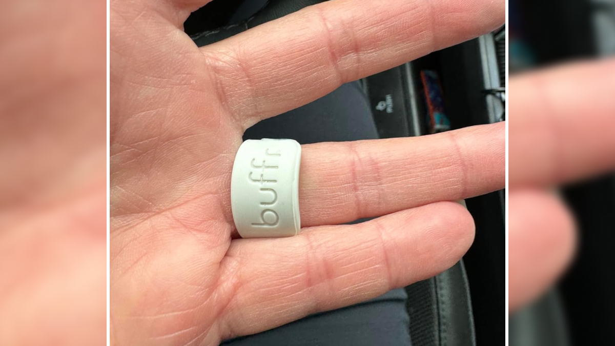 Hand holding a white silicone buffer designed for protecting fingers from nail damage in hyper specific life issues.