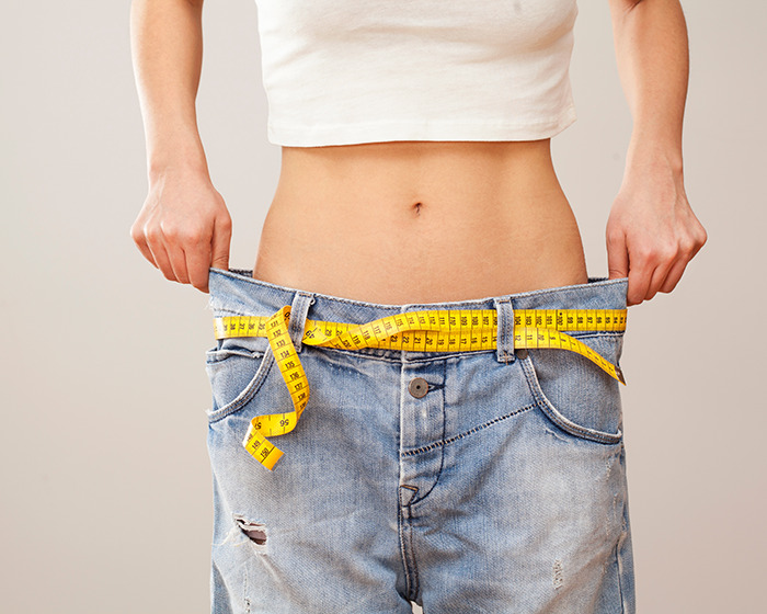 Person wearing oversized jeans with a yellow measuring tape around the waist symbolizing organ-destroying effects of Ozempic and Mounjaro. Person wearing oversized jeans with a yellow measuring tape around the waist symbolizing organ-destroying effects of Ozempic and Mounjaro.