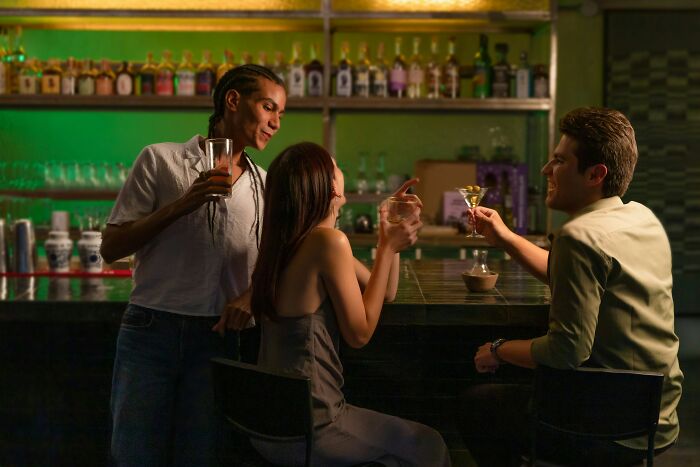 Three people at a bar holding drinks and chatting, illustrating dates that went sour and the use of a safe word.
