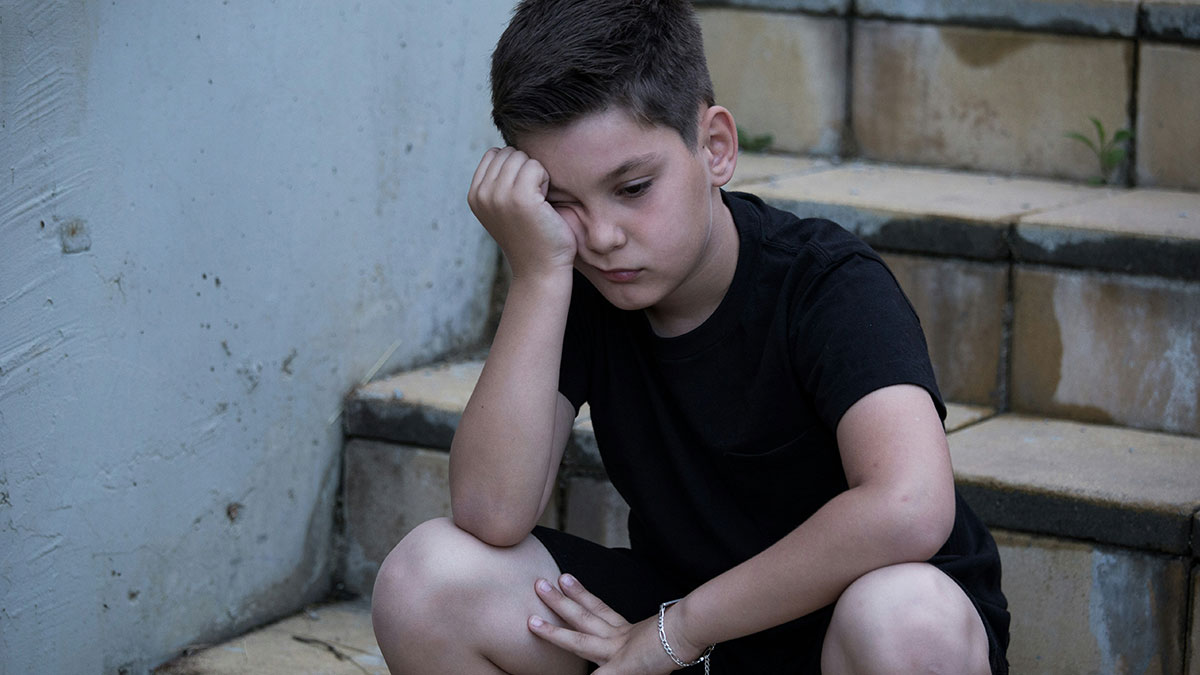 Sad boy sitting alone on steps, reflecting the pain of parents who disowned their children in difficult family situations.