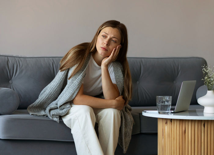Young woman sitting on a couch looking upset, reflecting on damaged car, dishes, and furniture in relationship conflict scenario. Young woman sitting on a couch looking upset, reflecting on damaged car, dishes, and furniture in relationship conflict scenario.