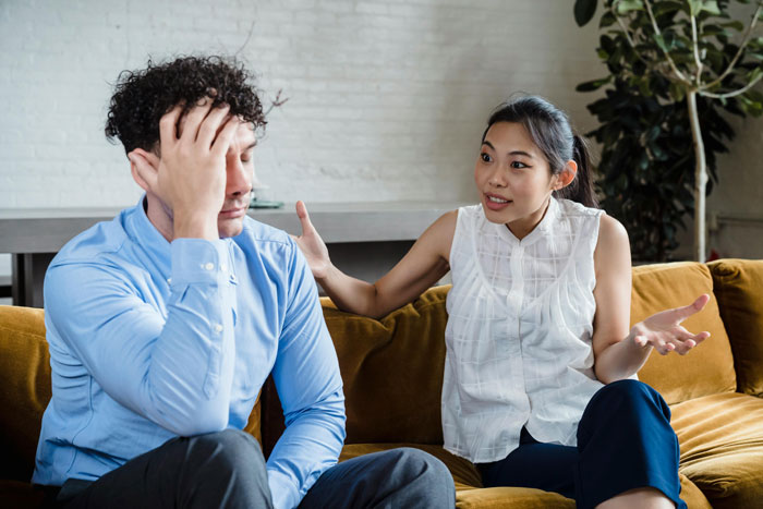 Couple arguing on couch, boyfriend upset and girlfriend explaining, illustrating damage and victim playing in relationship conflict. Couple arguing on couch, boyfriend upset and girlfriend explaining, illustrating damage and victim playing in relationship conflict.