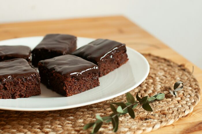 Chocolate brownies with glossy frosting served on a white plate representing surprising foods banned in the USA.