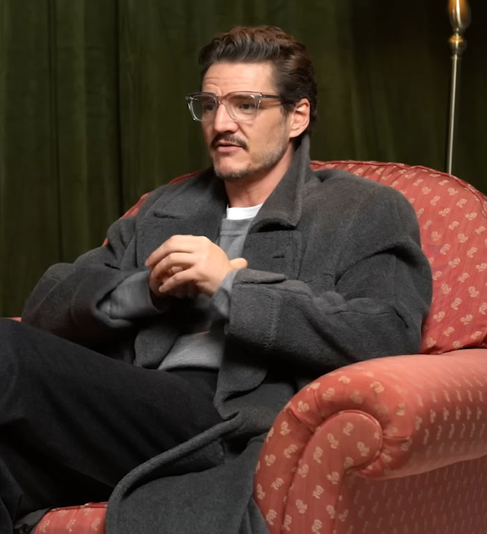 Pedro Pascal seated in a gray coat and glasses, discussing his criticism of JK Rowling in an indoor interview setting. Pedro Pascal seated in a gray coat and glasses, discussing his criticism of JK Rowling in an indoor interview setting.
