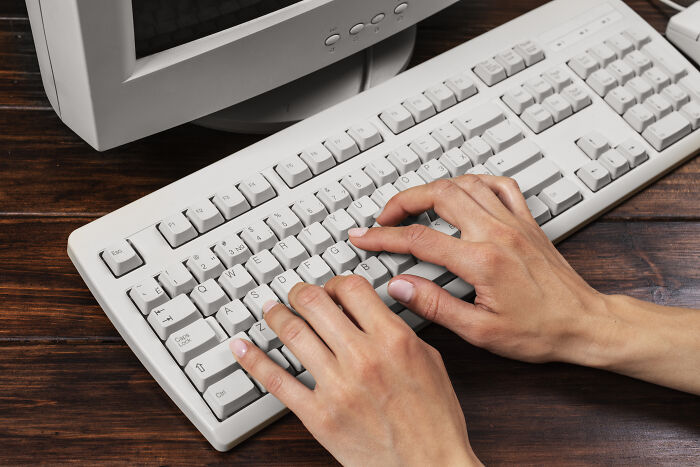 Hands typing on an old computer keyboard and CRT monitor showcasing skills people online needed before the 2000s.