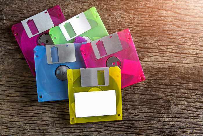 Colorful floppy disks scattered on a wooden surface representing outdated skills people online needed before the 2000s.