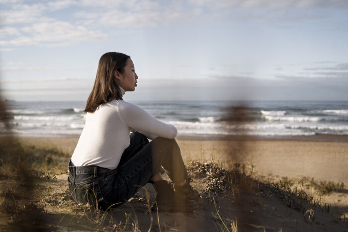 Young woman sitting on the beach, reflecting on past skills people online needed before the 2000s but no longer use.