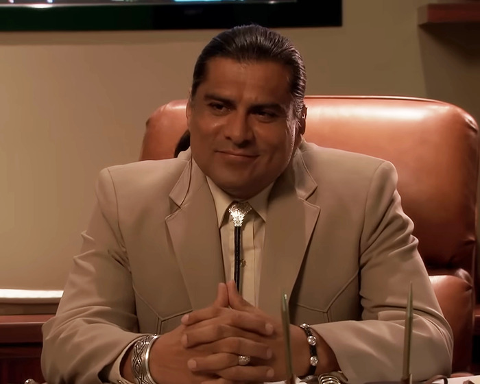 Man in beige suit sitting at desk, linked to discussions about Chris Pratt and Parks And Rec co-star tribute controversy. Man in beige suit sitting at desk, linked to discussions about Chris Pratt and Parks And Rec co-star tribute controversy.