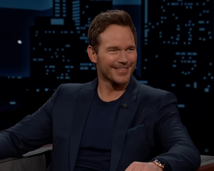 Chris Pratt smiling in a dark suit during a talk show, sparking heated reactions after Parks and Rec tribute. Chris Pratt smiling in a dark suit during a talk show, sparking heated reactions after Parks and Rec tribute.