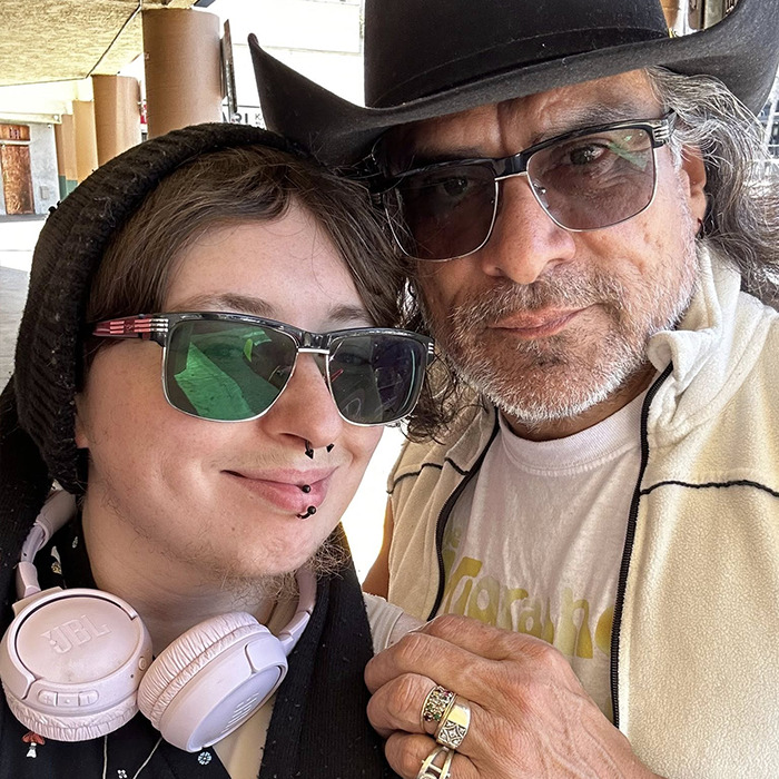 Person with sunglasses and headphones posing with a man in a hat and glasses, sparking heated reactions to Chris Pratt tribute. Person with sunglasses and headphones posing with a man in a hat and glasses, sparking heated reactions to Chris Pratt tribute.