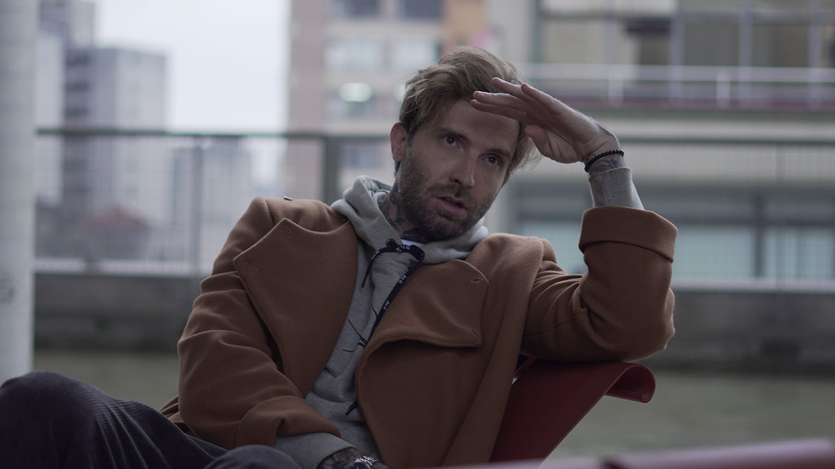 Man in a brown coat and hoodie looking distressed and reflective, symbolizing people ruining their life with one wrong deed.