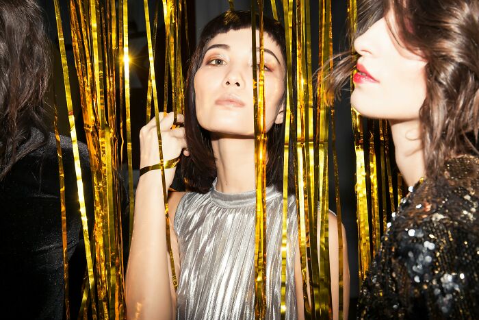 Two stylish adults posing behind gold streamers, showcasing their high school glory days with confident expressions.