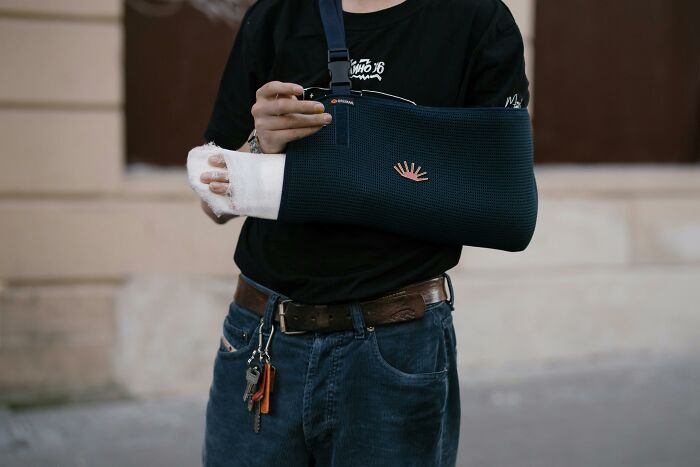 Person with a broken arm in a sling, symbolizing consequences of coworker diabolical things before reporting to HR.