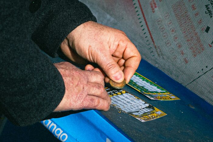 Hands scratching a dollar lottery ticket, illustrating tales of winning a priceless reward after spending just a dollar.