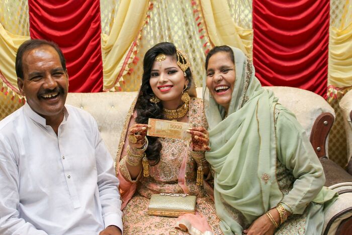 Wife embraces husband's culture in traditional attire, sharing a joyful moment with family during a festive celebration.