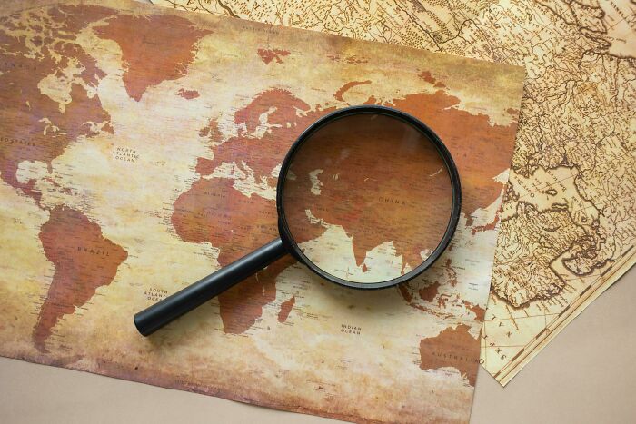 Vintage world map with a magnifying glass focused on Asia, highlighting geography quiz challenge concept. Vintage world map with a magnifying glass focused on Asia, highlighting geography quiz challenge concept.