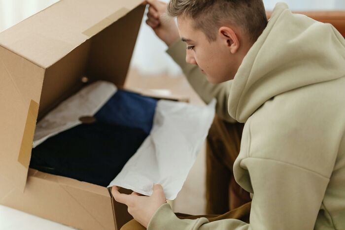 Young man opening a cardboard box.