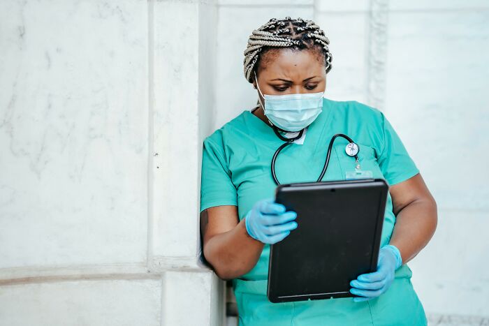Healthcare worker in scrubs and mask reviewing tablet, representing stories of people ruining their entire life with one wrong deed.