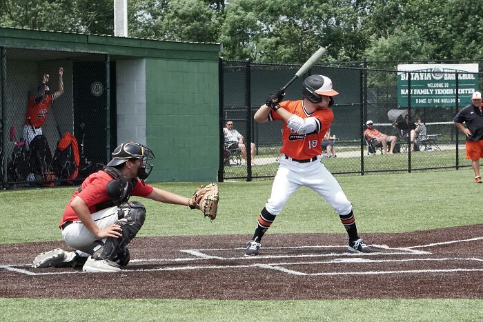 Adult baseball players in orange and red uniforms showing they never moved on from their glory days in high school.
