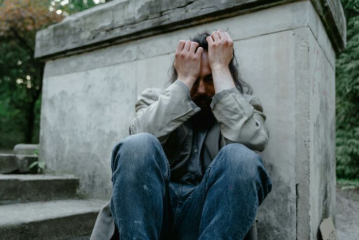 Man sitting outside with head in hands, illustrating emotions linked to people share most privileged things said.