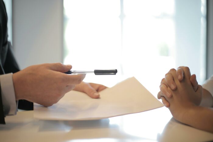 Two people sharing a document at a bright table, illustrating people share most privileged things said concept.