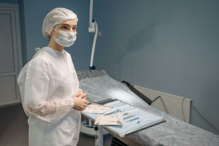 Medical professional in protective gear preparing instruments, symbolizing coworker diabolical things report HR concerns.