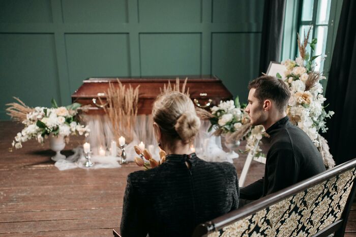 Two people sitting in a funeral setting.