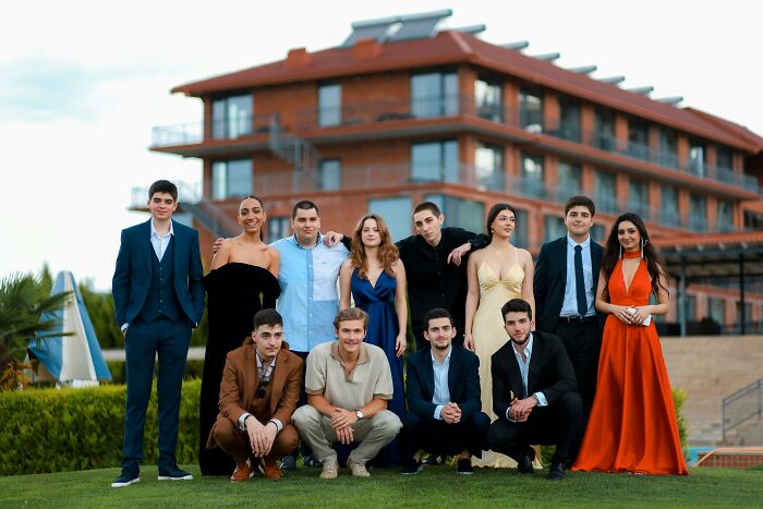 Group of adults dressed formally outdoors, showing they never moved on from their high school glory days in style.