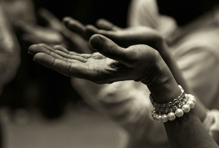 Open hands raised in a gesture of prayer or meditation, symbolizing contemplation of theories about the afterlife.