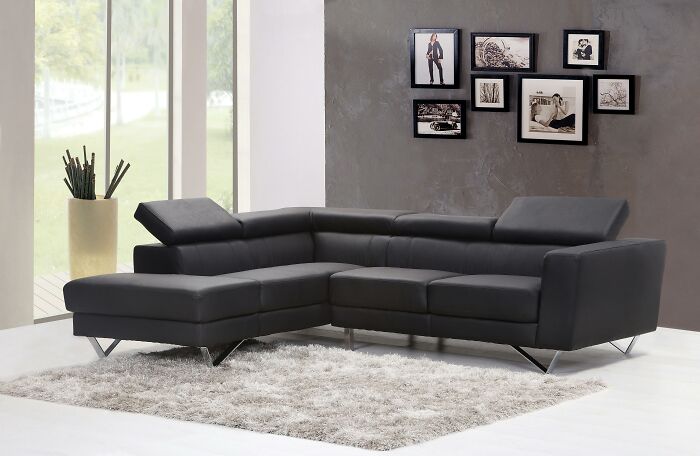 Modern black leather sectional sofa in a bright living room.