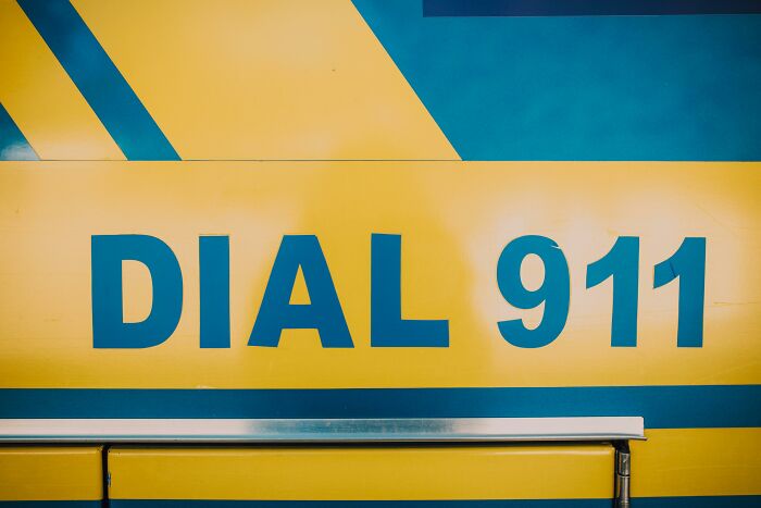 Close-up of a yellow and blue emergency vehicle displaying dial 911, symbolizing reporting coworker diabolical things to HR.