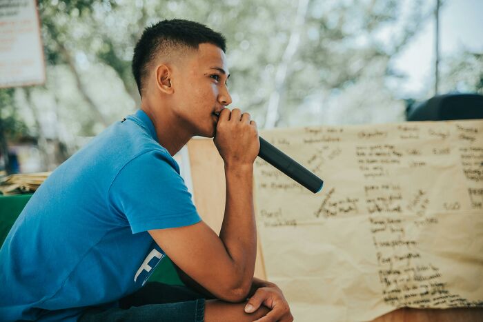 Young man holding a microphone and thinking, illustrating the challenge to prove you are smarter by guessing languages in a quiz. Young man holding a microphone and thinking, illustrating the challenge to prove you are smarter by guessing languages in a quiz.