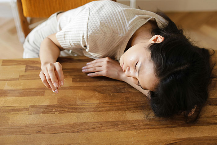 Woman lying on wooden table holding wedding ring, reflecting on wedding dress sisters drama in a quiet room. Woman lying on wooden table holding wedding ring, reflecting on wedding dress sisters drama in a quiet room.