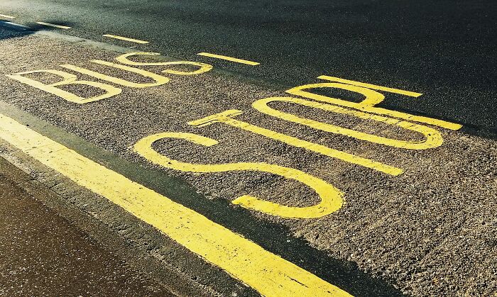 Bus stop markings on the asphalt road with bright yellow lines, symbolizing places people share most privileged things said.