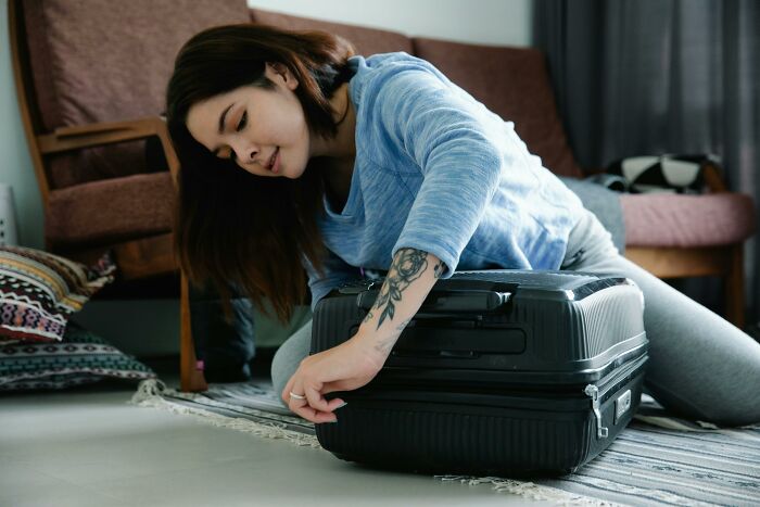 Woman packing a suitcase at home, preparing for travel to avoid being held up in security line before boarding. Woman packing a suitcase at home, preparing for travel to avoid being held up in security line before boarding.