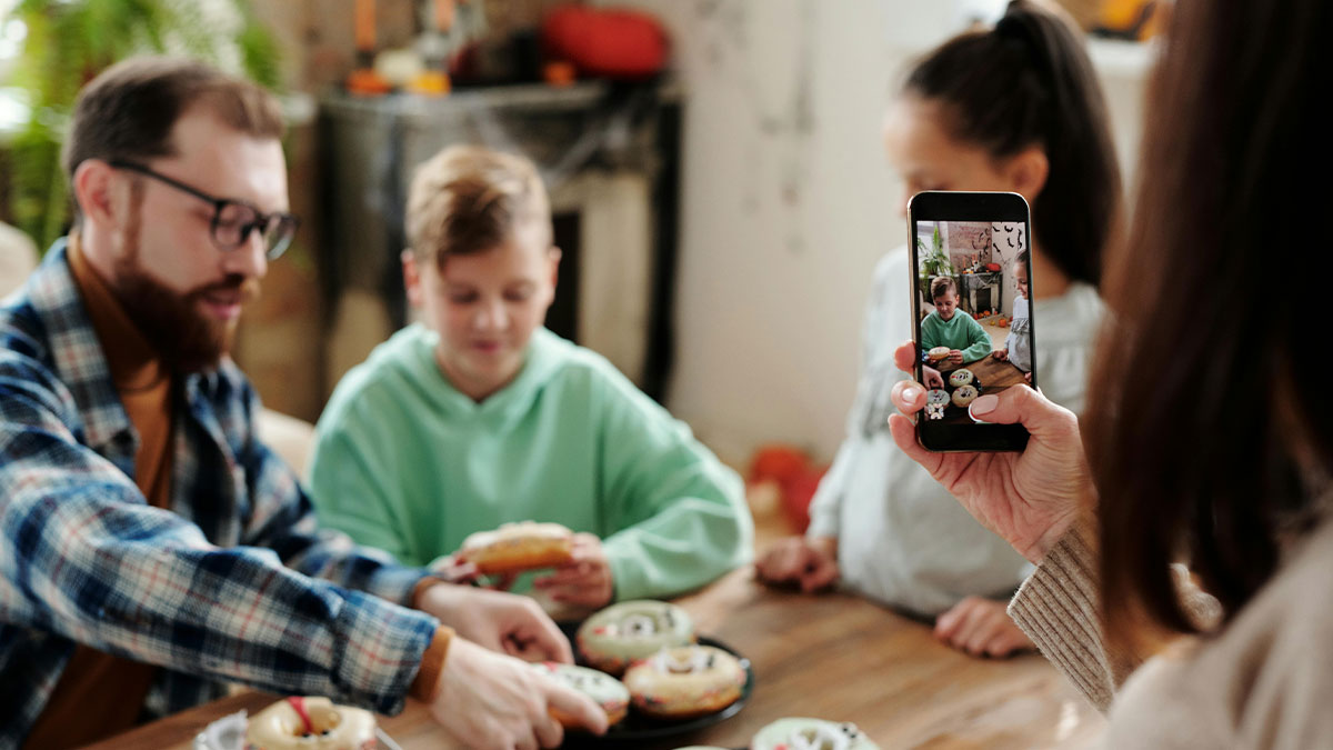 Person taking photo of family enjoying bagels at table, illustrating insights from poor folks who dated wealthy people