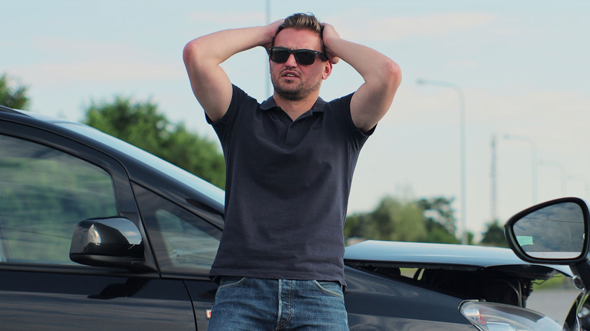 Man in sunglasses frustrated near two damaged cars after parking Porsche across three handicap spots in parking lot.