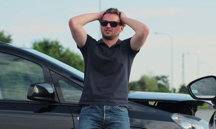 Man wearing sunglasses and a black shirt stands frustrated next to his Porsche parked across three handicap spots. Man wearing sunglasses and a black shirt stands frustrated next to his Porsche parked across three handicap spots.