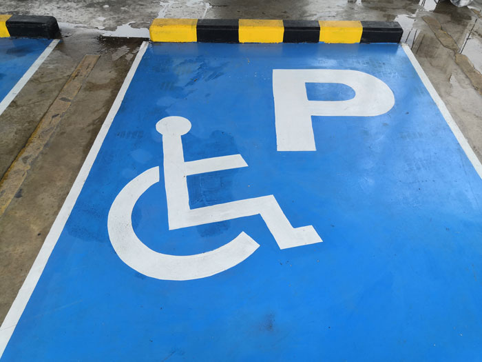 Handicap parking spot marked with wheelchair symbol and letter P in a blue reserved parking space. Handicap parking spot marked with wheelchair symbol and letter P in a blue reserved parking space.